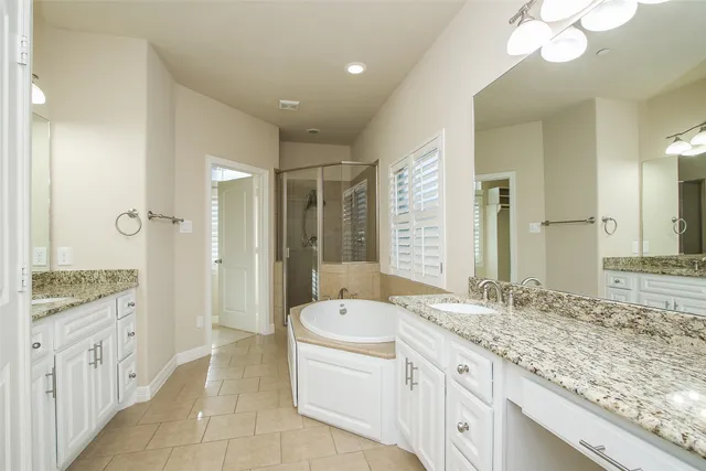 a spacious bathroom with a granite countertop sink a toilet a mirror and shower