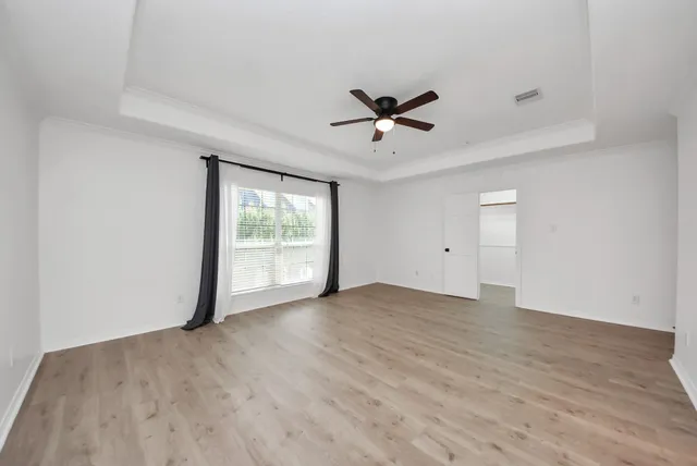 a view of empty room with wooden floor and fan