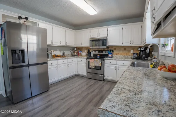 a kitchen with stainless steel appliances granite countertop a refrigerator sink and white cabinets