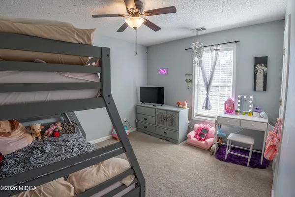 a bedroom with furniture a flat screen tv and a window