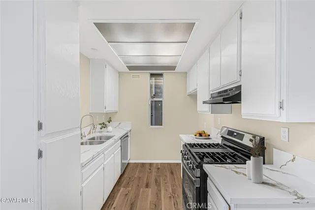 a kitchen with stainless steel appliances a stove a sink and white cabinets
