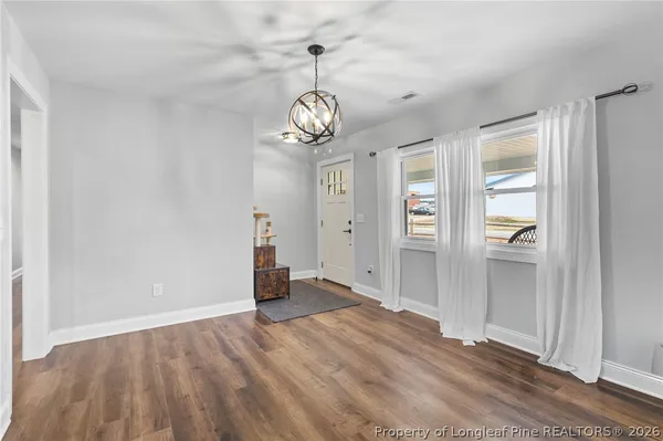 an empty room with wooden floor cabinet and windows