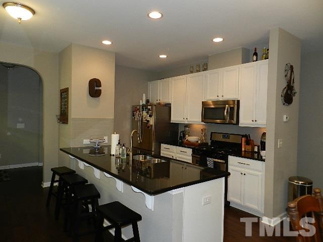 688 Wickham Ridge Road Apex, NC 27539 - Photo 3 of 20 a kitchen with white cabinets a sink and stainless steel appliances