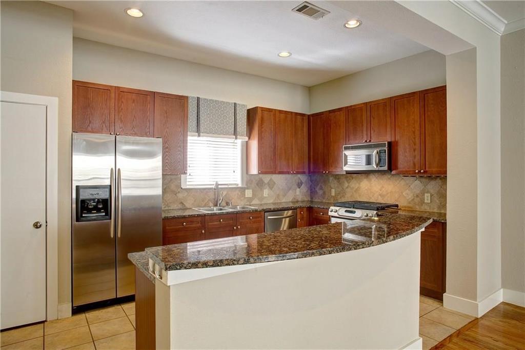 Kitchen with backsplash, sink, stainless steel appliances, and light tile floors