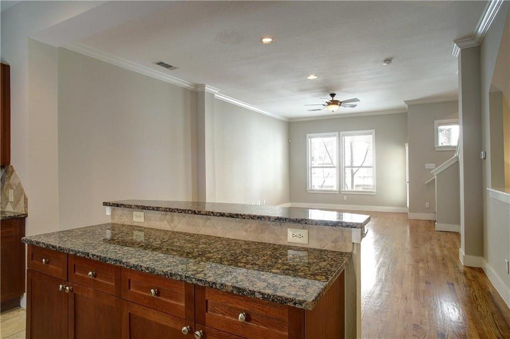 4830 Cedar Springs Road, Unit 43 Dallas, TX 75219 - Photo 3 of 22 Kitchen with light hardwood / wood-style flooring, ceiling fan, dark stone counters, a center island, and ornamental molding