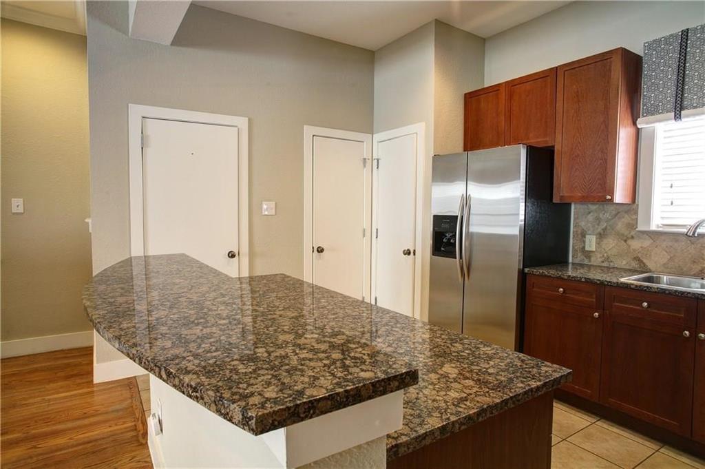 4830 Cedar Springs Road, Unit 43 Dallas, TX 75219 - Photo 7 of 22 Kitchen featuring stainless steel fridge with ice dispenser, tasteful backsplash, dark stone countertops, sink, and a center island