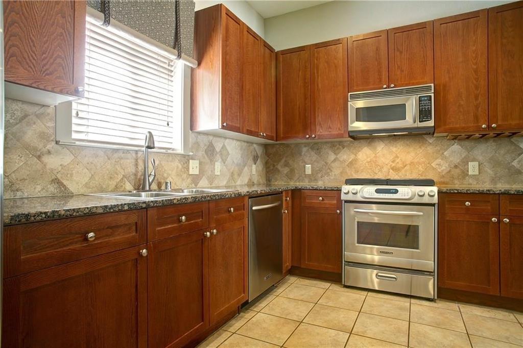 4830 Cedar Springs Road, Unit 43 Dallas, TX 75219 - Photo 8 of 22 Kitchen featuring light tile flooring, appliances with stainless steel finishes, sink, tasteful backsplash, and dark stone countertops