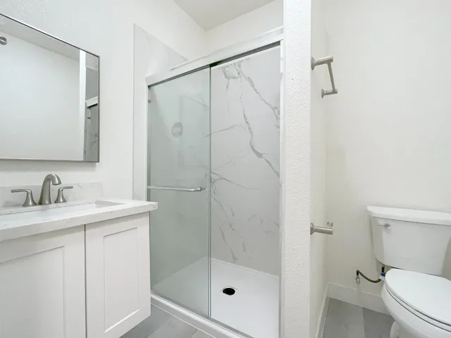 a bathroom with a granite countertop sink a toilet and shower