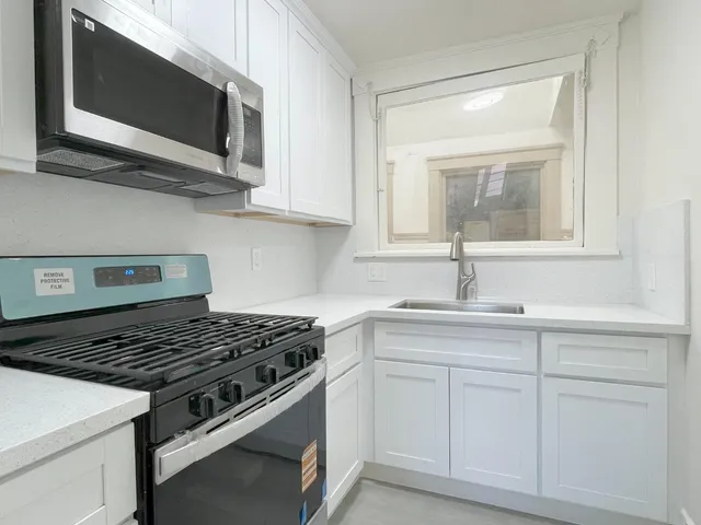a kitchen with white cabinets and appliances