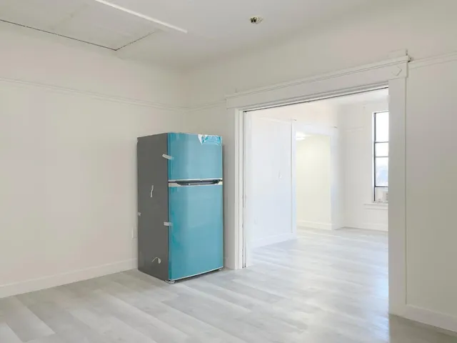 a view of a room with a refrigerator and wooden floor