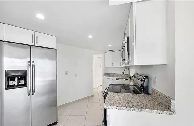 a kitchen with a refrigerator a sink a counter top space and cabinets