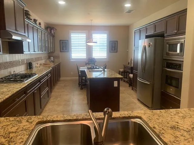 a kitchen with stainless steel appliances granite countertop a sink refrigerator and microwave