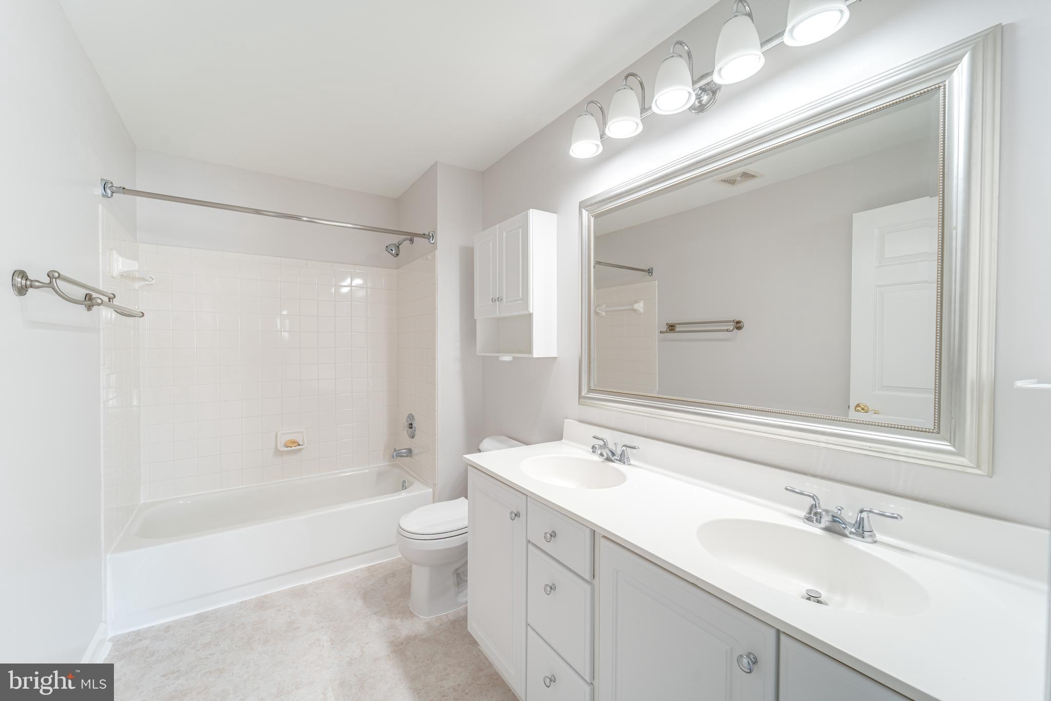 9220 Cardinal Forest Lane, Unit E Lorton, VA 22079 - Photo 20 of 26 a bathroom with a double vanity sink toilet mirror and bathtub