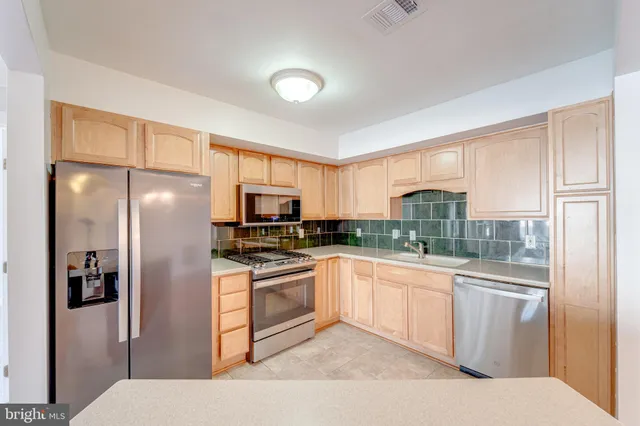a kitchen with stainless steel appliances granite countertop a refrigerator a stove and a sink