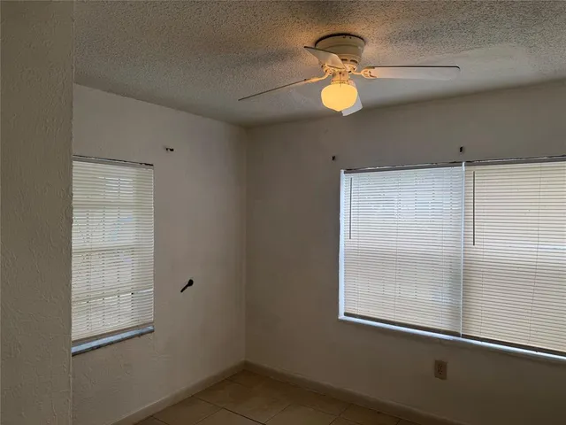 an empty room with windows and fan