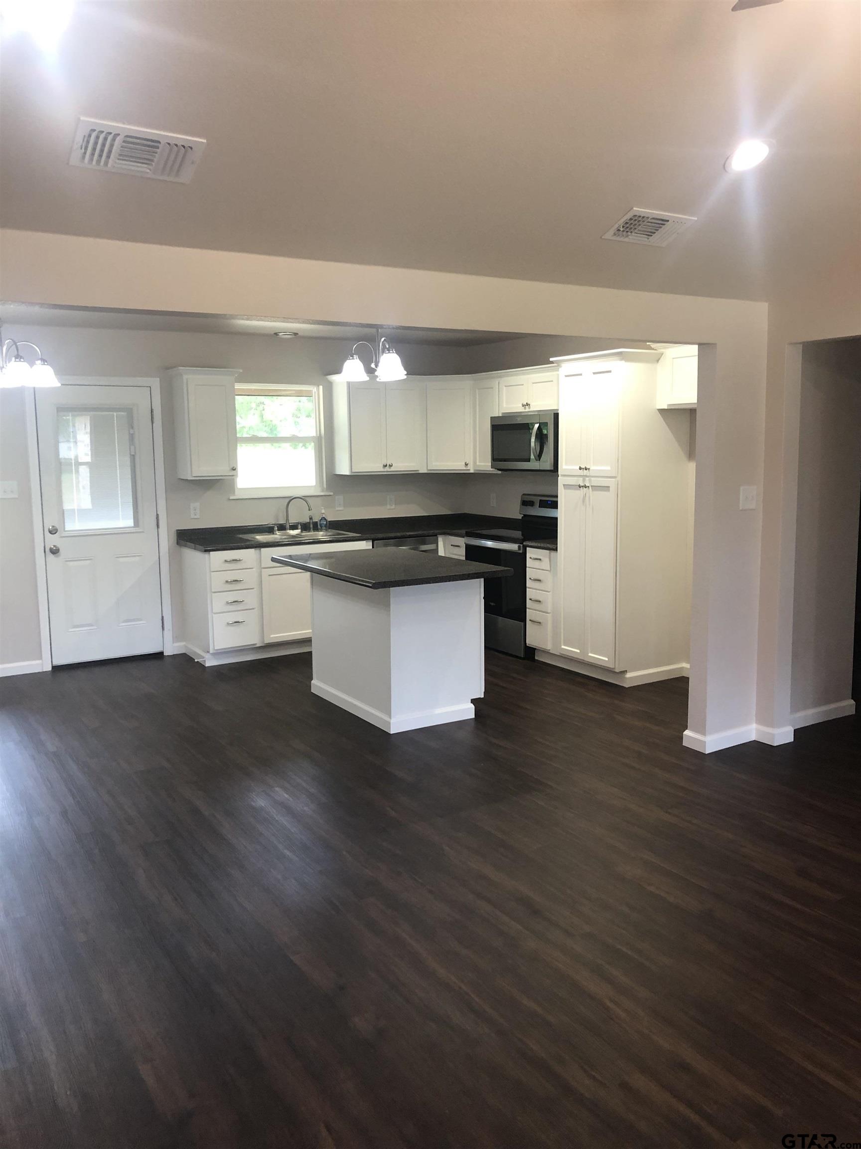 107 Meadow Lane Naples, TX 75568 - Photo 4 of 16 a kitchen with granite countertop a stove and wooden floor