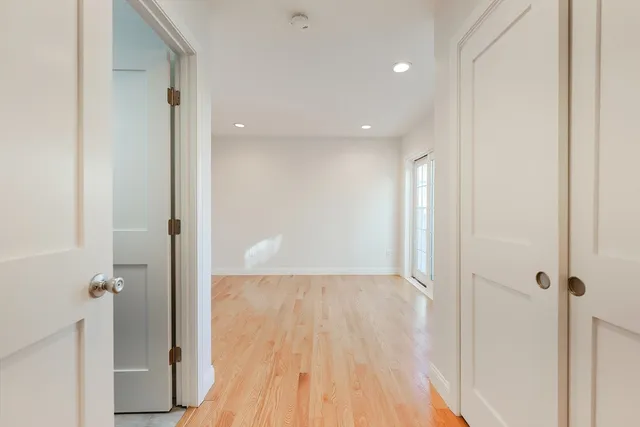 a view of a hallway with wooden floor and a bathroom