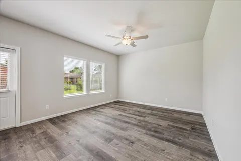 an empty room with windows and fan