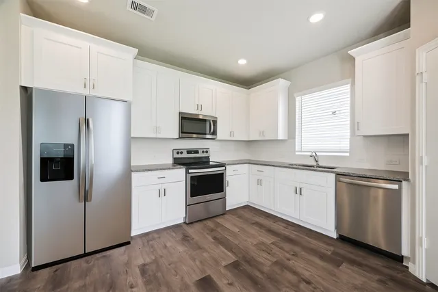 a kitchen with white cabinets stainless steel appliances and a window