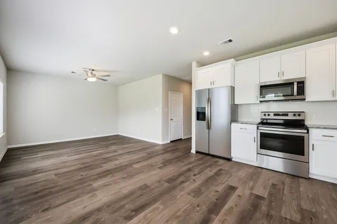 a kitchen with granite countertop a refrigerator and a stove top oven