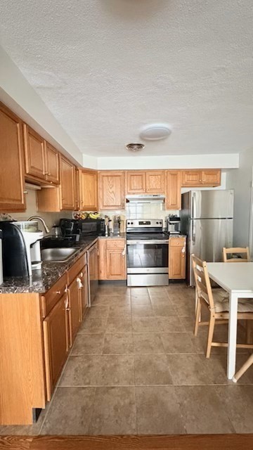 1105 Lexington Street, Unit 84 Waltham, MA 02452 - Photo 5 of 9 a kitchen with stainless steel appliances kitchen island granite countertop a stove top oven a sink a dining table and chairs