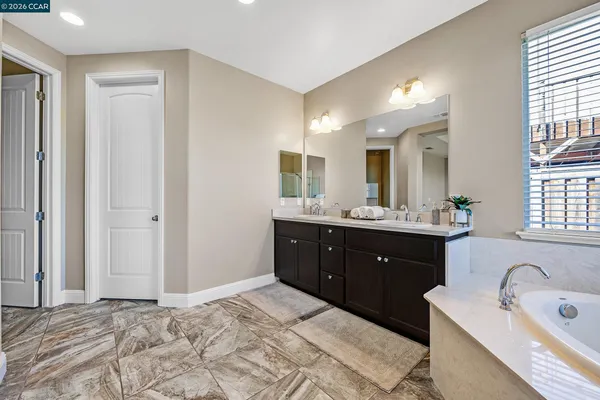 a spacious bathroom with a double vanity sink a mirror and a bathtub