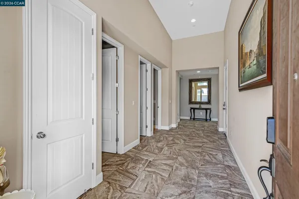 a view of a hallway to a livingroom with wooden floor and windows