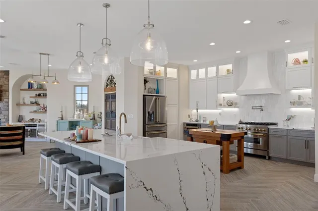 a large kitchen with stainless steel appliances kitchen island granite countertop a stove a sink a refrigerator and a dining table with wooden floor