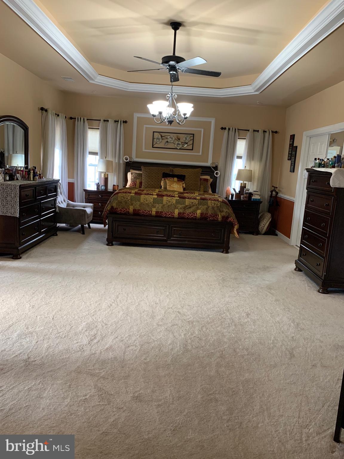 14205 Derby Ridge Road Bowie, MD 20721 - Photo 24 of 53 a spacious bedroom with a bed a chandelier and a television