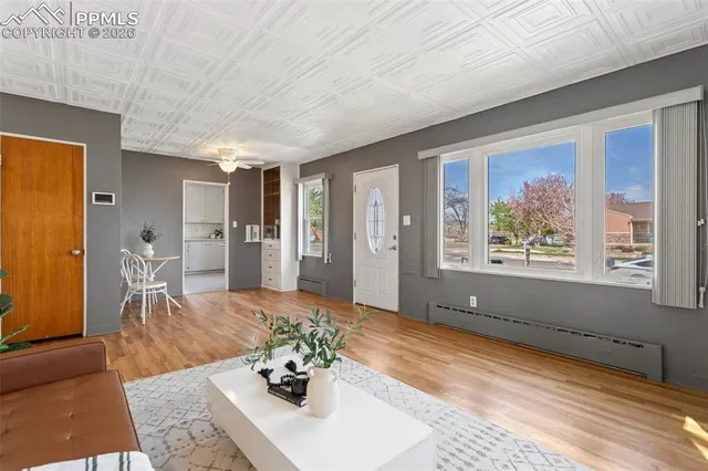 a living room with stainless steel appliances furniture a rug and a large window