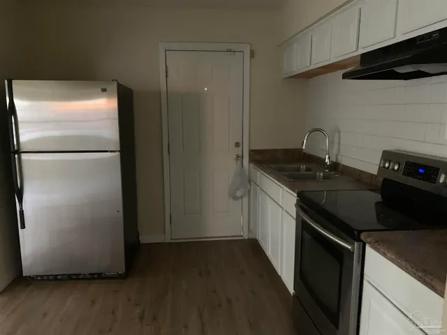 a kitchen with a refrigerator a stove and wooden floor