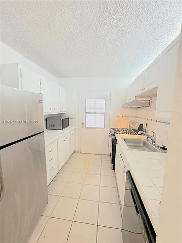a kitchen with a sink a stove a refrigerator and white cabinets
