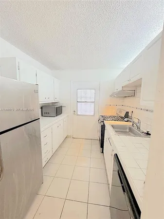a kitchen with a sink a stove a refrigerator and white cabinets