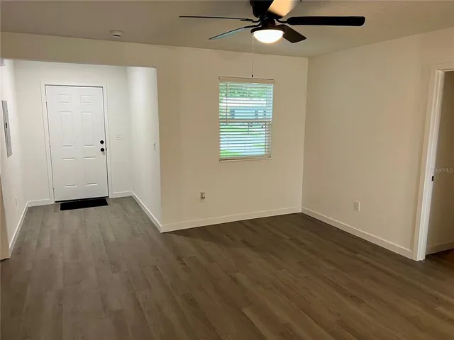 an empty room with a hardwood and ceiling fan