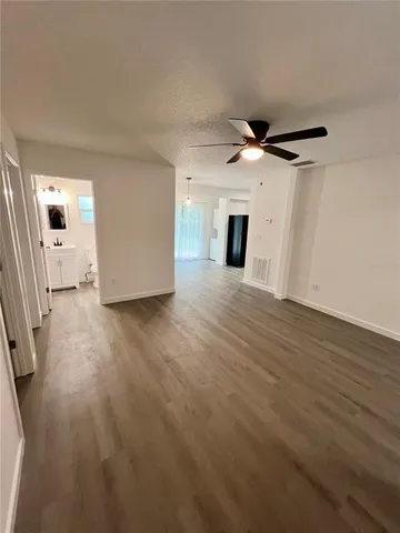 an empty room with wooden floor fireplace and windows