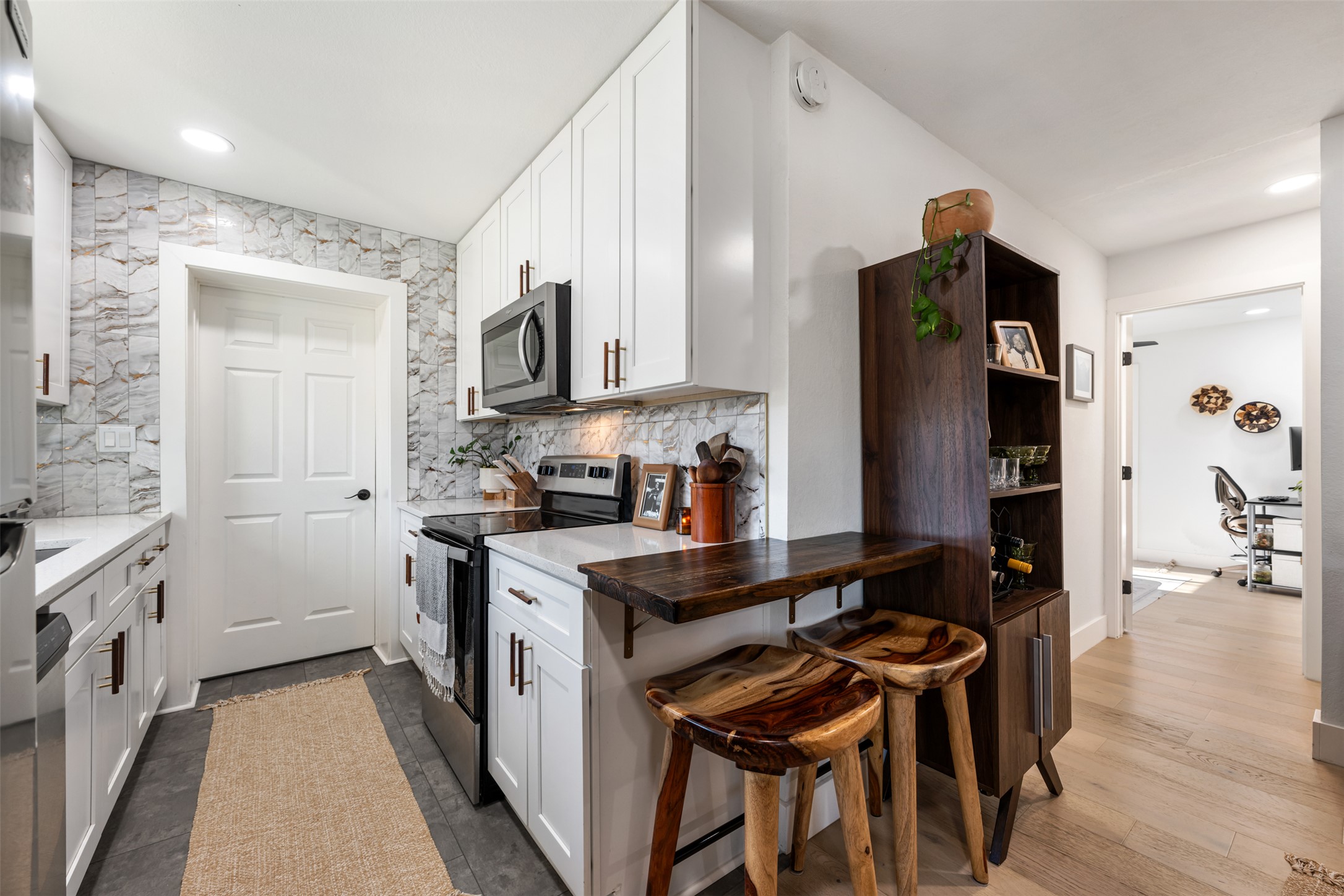 1616 Webberville Road, Unit A Austin, TX 78721 - Photo 18 of 35 Kitchen with white cabinets, appliances with stainless steel finishes, recessed lighting, backsplash, and dark stone counters