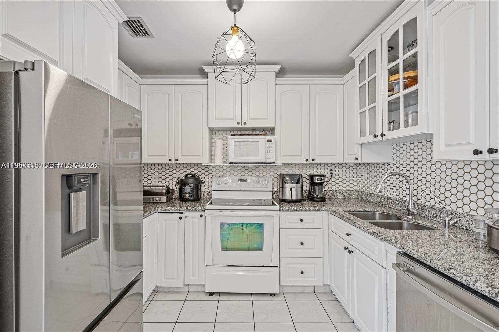 6418 Southwest 39th Terrace Miami, FL 33155 - Photo 9 of 24 a kitchen with white cabinets and refrigerator
