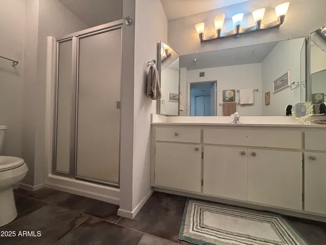 a spacious bathroom with a double vanity sink toilet mirror and shower