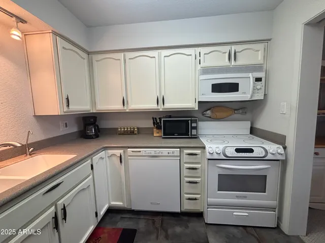 a kitchen with stainless steel appliances granite countertop white cabinets and a stove top oven