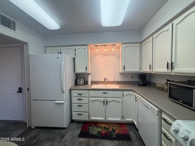 a kitchen with a refrigerator sink and cabinets