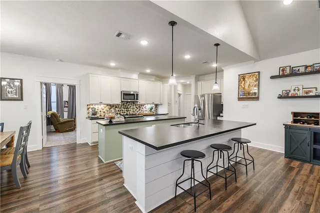 a kitchen with stainless steel appliances kitchen island granite countertop a sink and cabinets