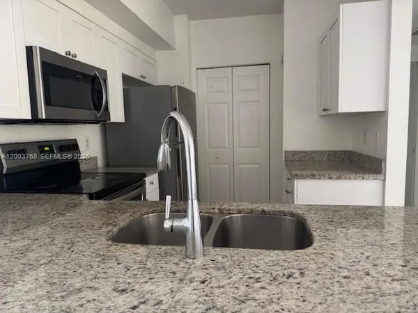 a kitchen with stainless steel appliances granite countertop a sink a microwave a refrigerator and a granite counter tops