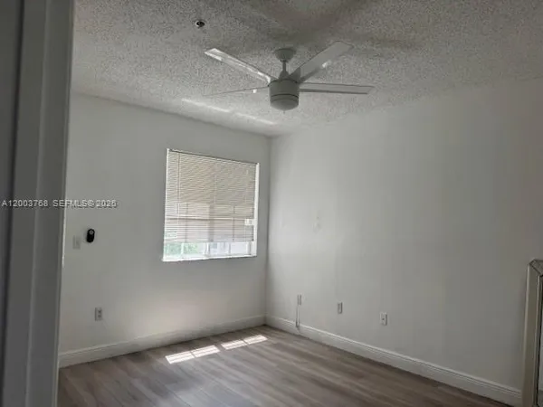 an empty room with wooden floor fan and windows