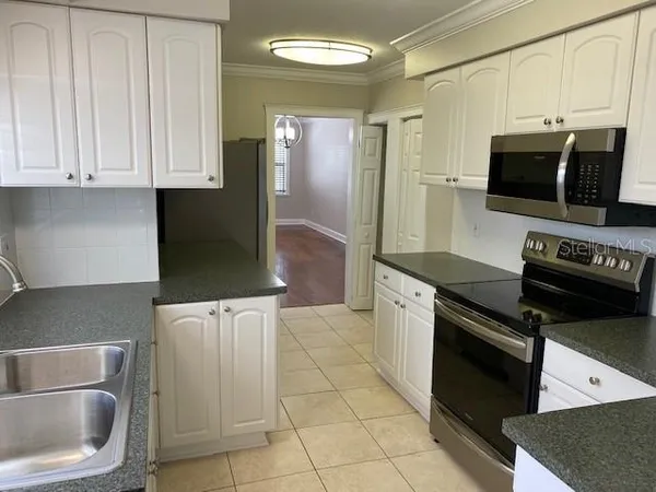 a kitchen with granite countertop a refrigerator and a stove top oven