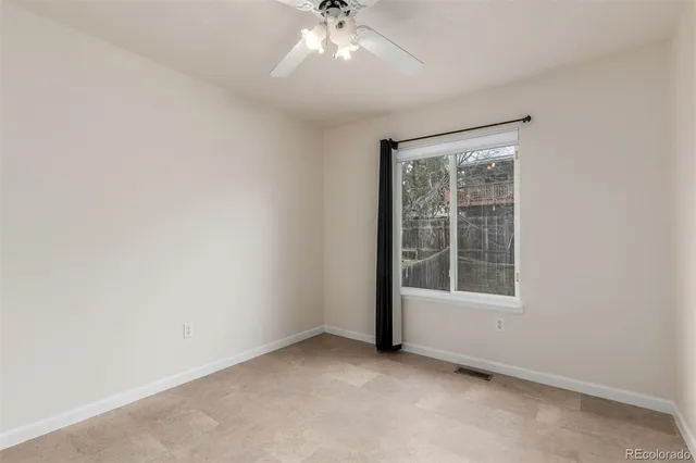an empty room with chandelier fan and windows