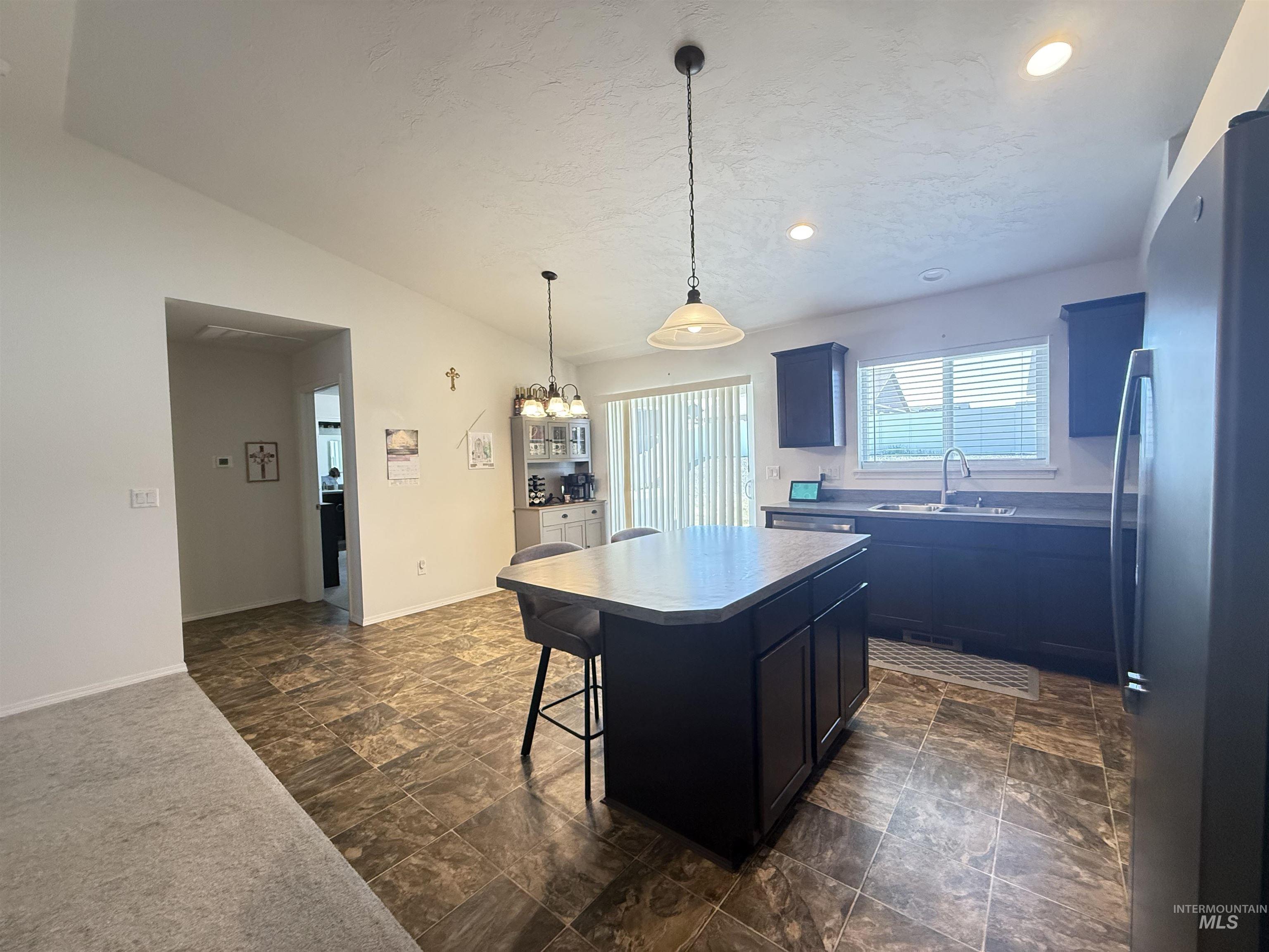 1556 Frontier Drive Lewiston, ID 83501 - Photo 13 of 23 Kitchen featuring a central island with seating, dark cabinetry, light-toned countertops, and durable tile-look flooring