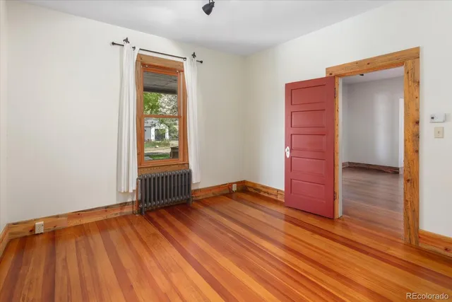 an empty room with wooden floor closet and windows