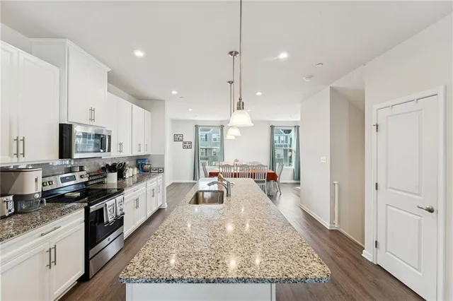 a large kitchen with kitchen island a large counter top space a sink stainless steel appliances and cabinets