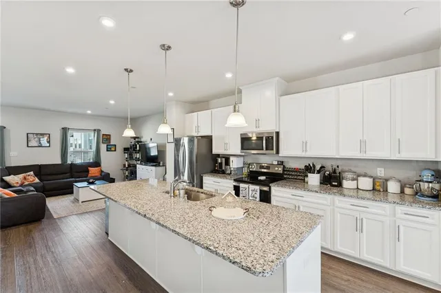 a kitchen with stainless steel appliances granite countertop a stove sink refrigerator and cabinets