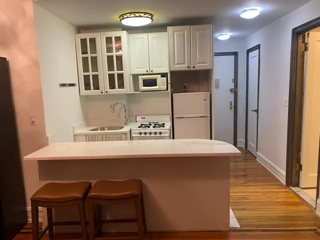 a kitchen with stainless steel appliances a table chairs refrigerator and sink